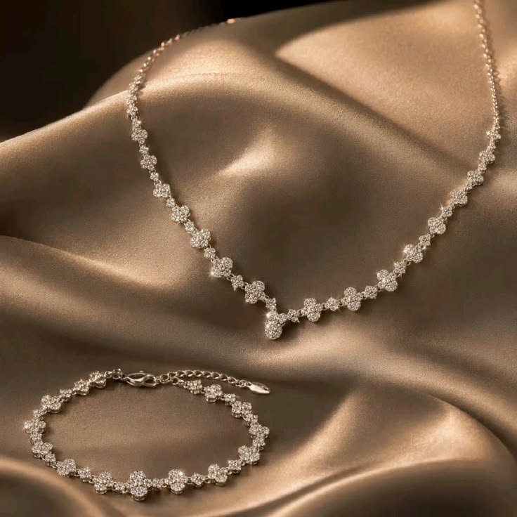 Elegant silver necklace and matching bracelet displayed on satin fabric
